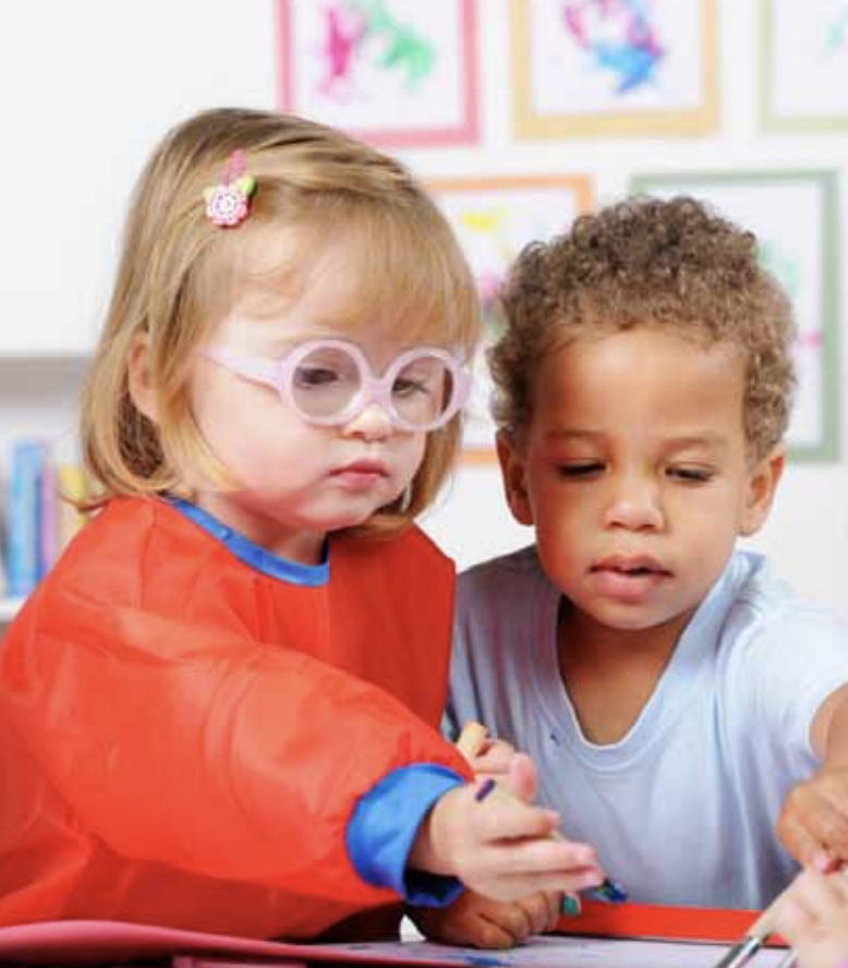 Two children color together in a preschool setting.