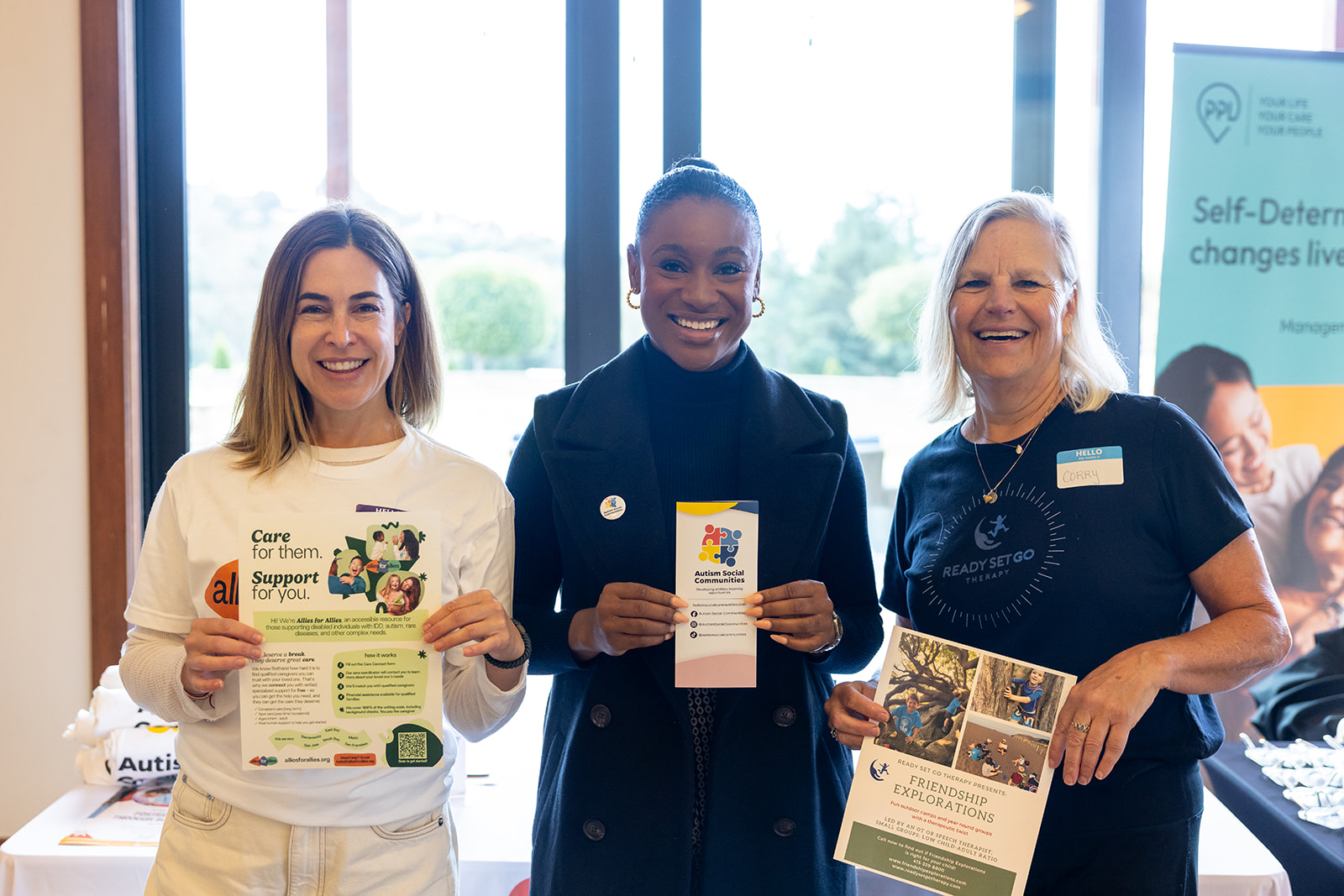 Three service providers at a Self-Determination Program event holding up flyers for their businesses.