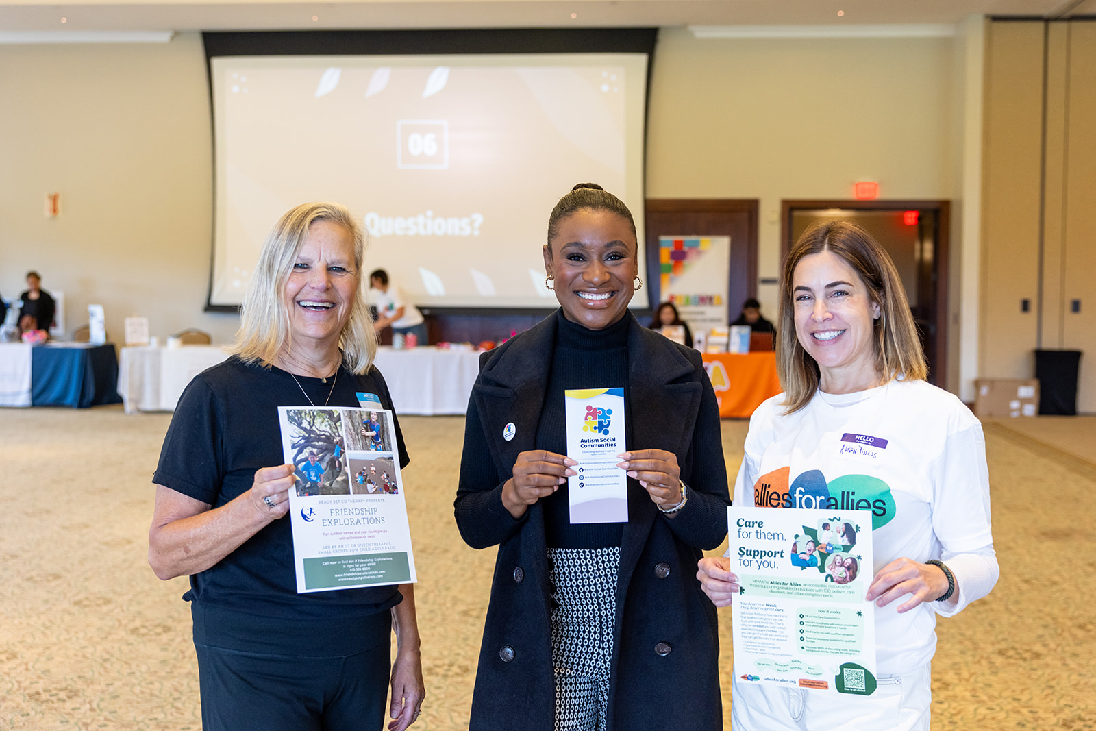 Three service providers at a Self-Determination Program event holding up flyers for their businesses.
