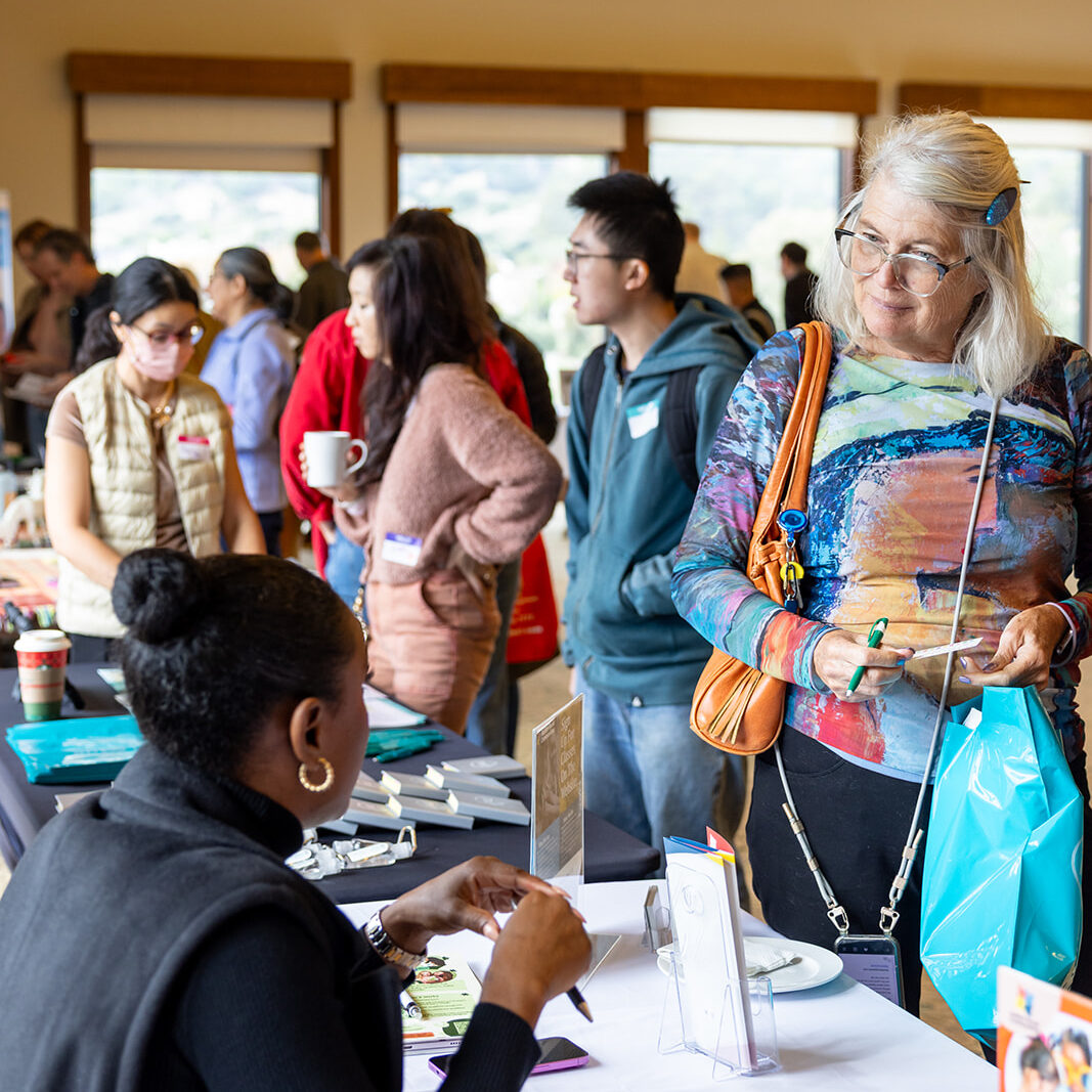 Woman picks up a flyer while listening to a vendor at the Marin Self-Determination Resource Fair.