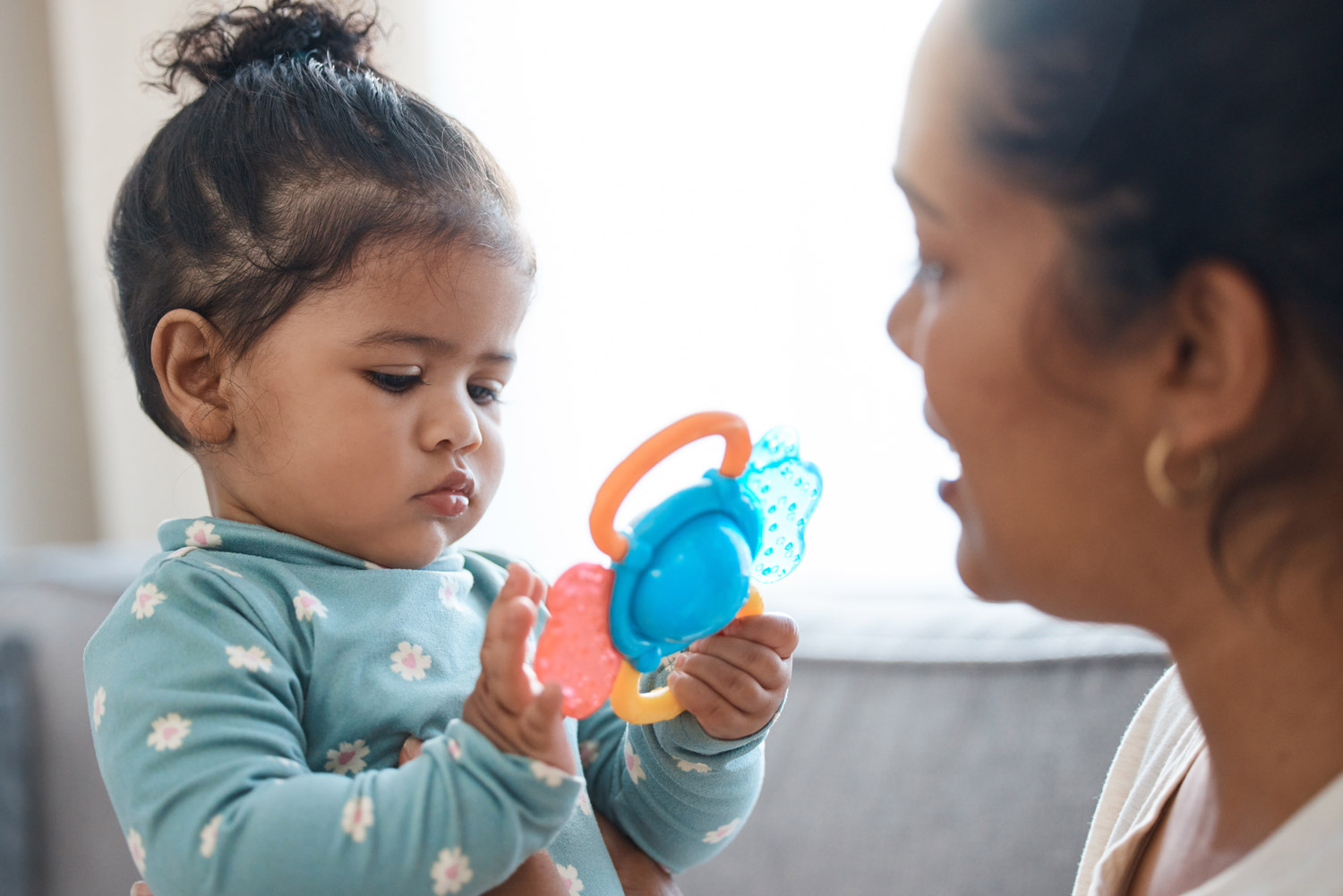 Over the shoulder photo of an adorable little girl playing with a toy while therapist talks to her.