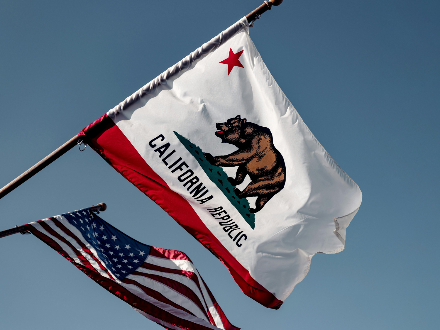 Close up of the California state flag and United States flag on a clear summer day.