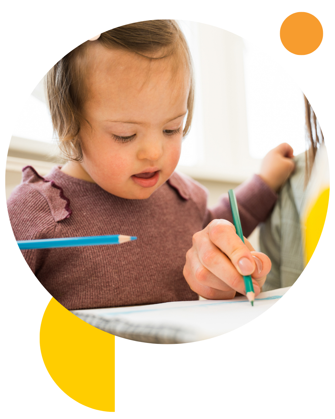 Two year old girl with Down Syndrome spending time drawing with her mother on a sheet of paper at the table.