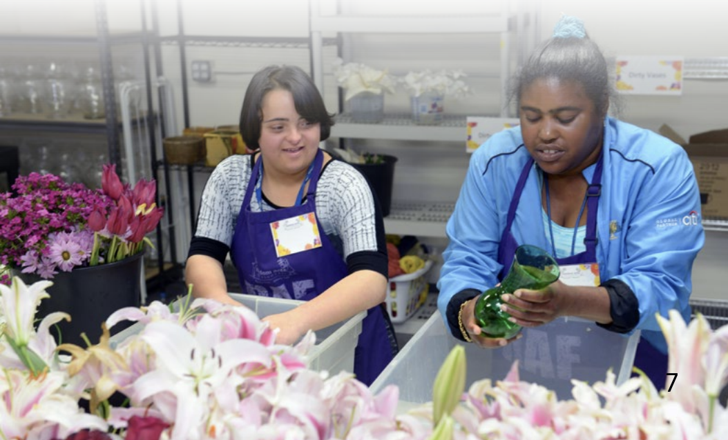 Two young women with disabilities trim and arrange flowers together.