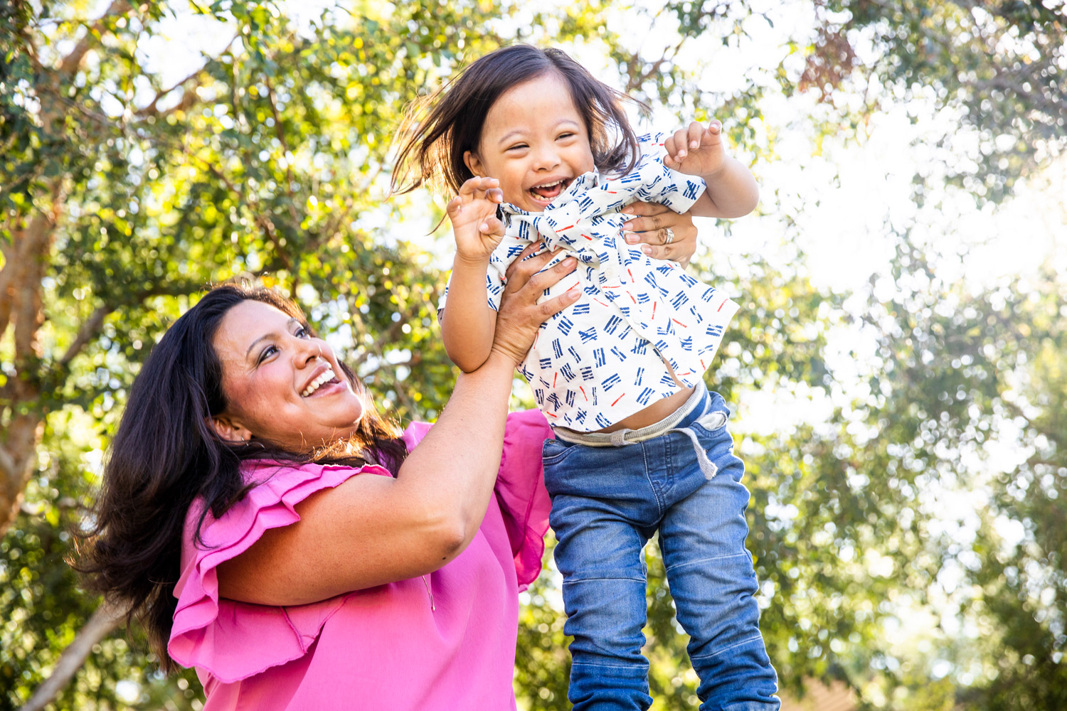 A mom lifts up her one-year old son with Downs Syndrome to fly in the air and he laughs.