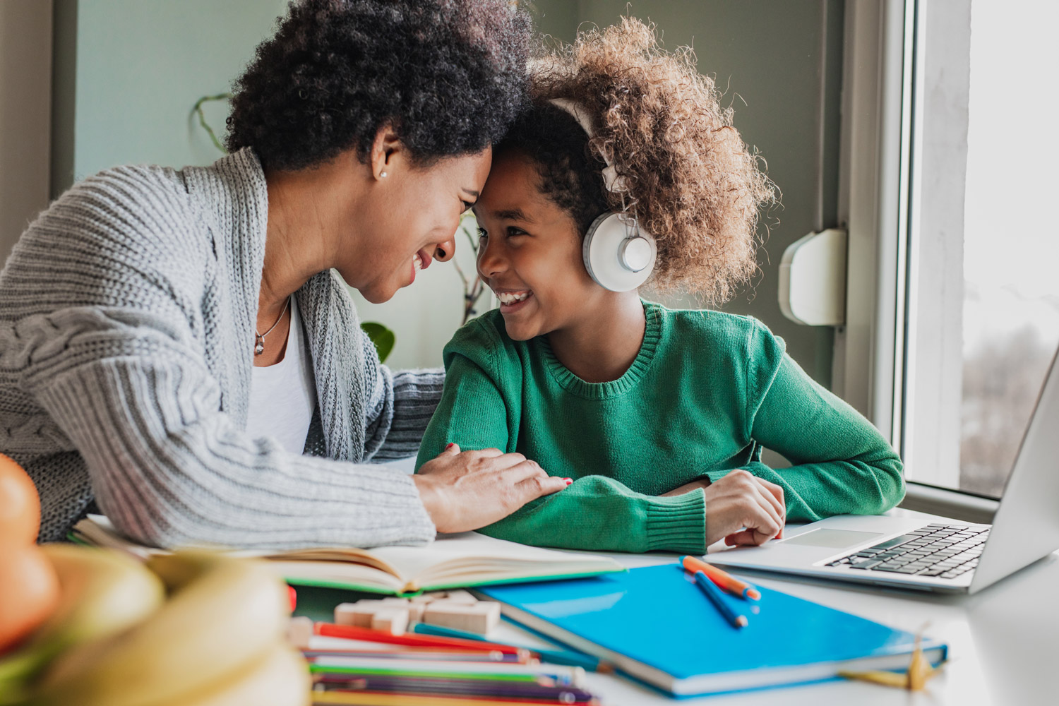 African American mother is helps her school-aged daughter with autism to study at home.