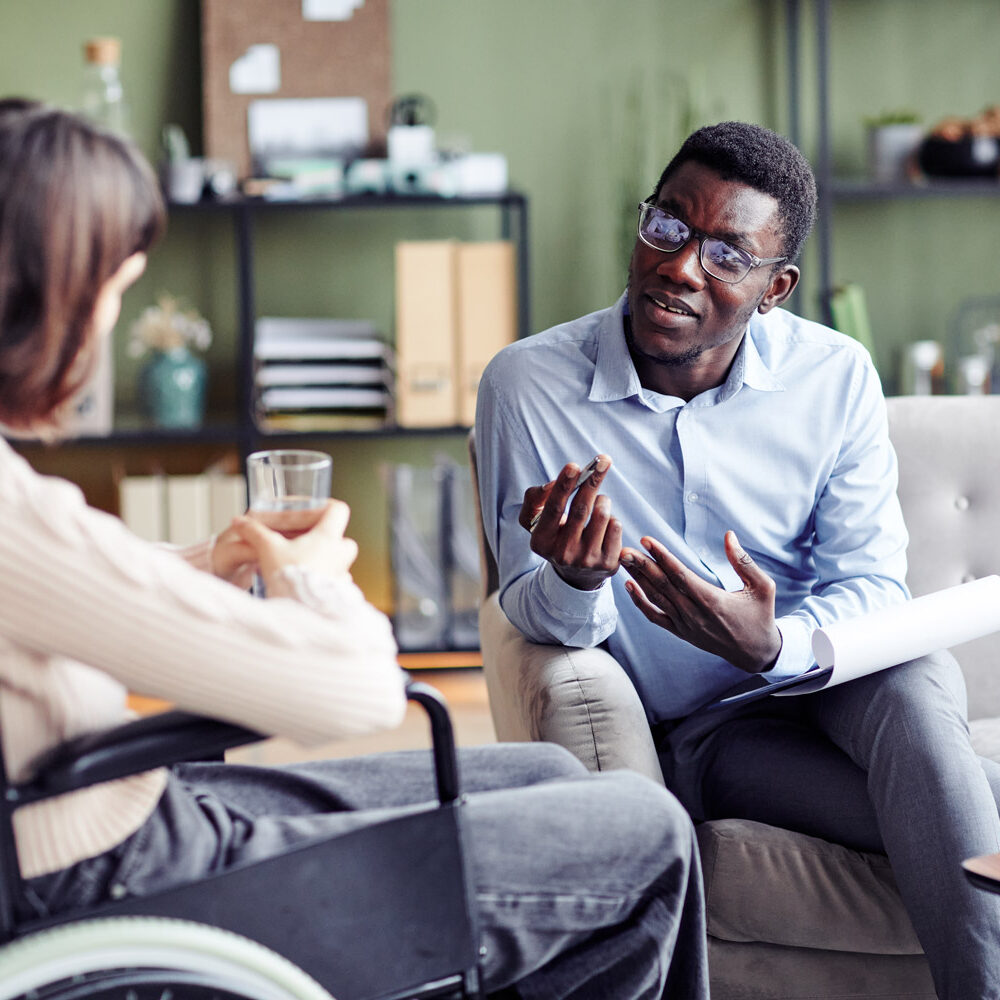 Black psychologist teaching a young woman with disability stress management and other coping skills.