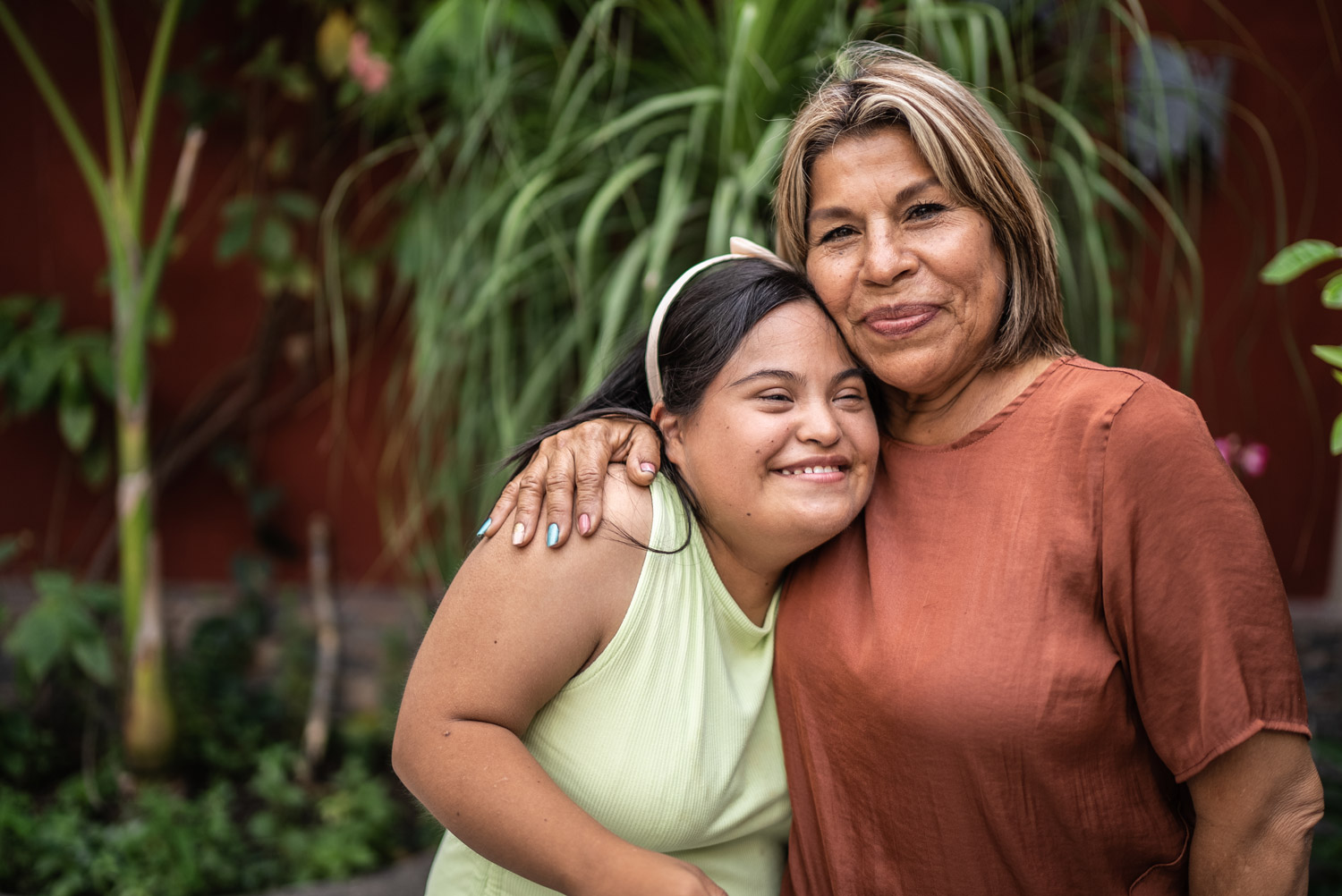 Outdoor portrait of mother embracing her daughter with Down Syndrome.