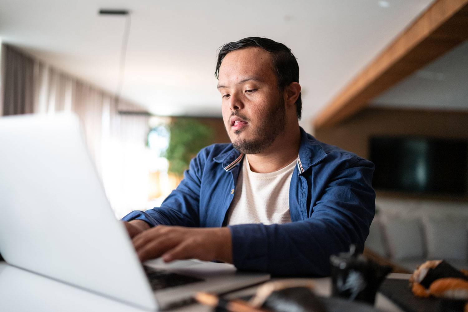 Young man with Down syndrome using the laptop at home.