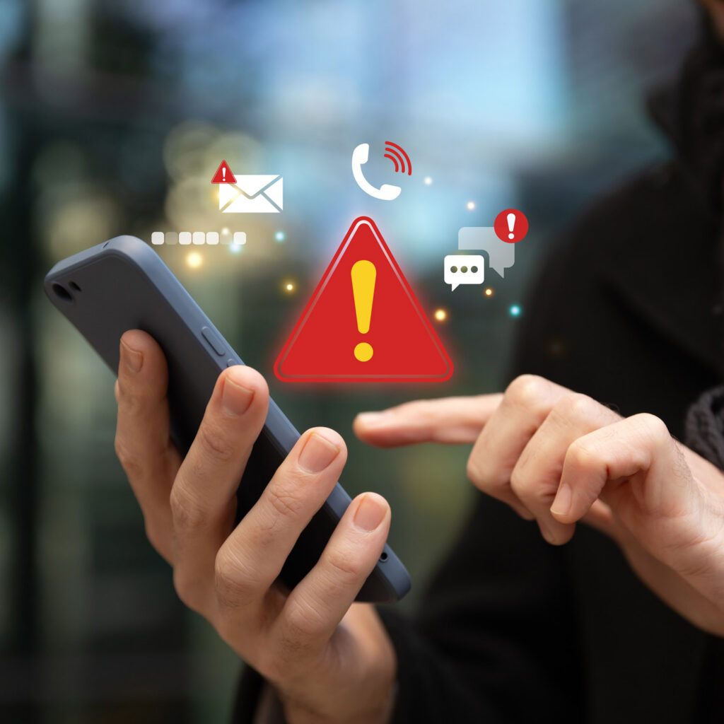 Pessoa a utilizar um smartphone com ícones de alerta vermelho e de aviso, que representam notificações de emergência.